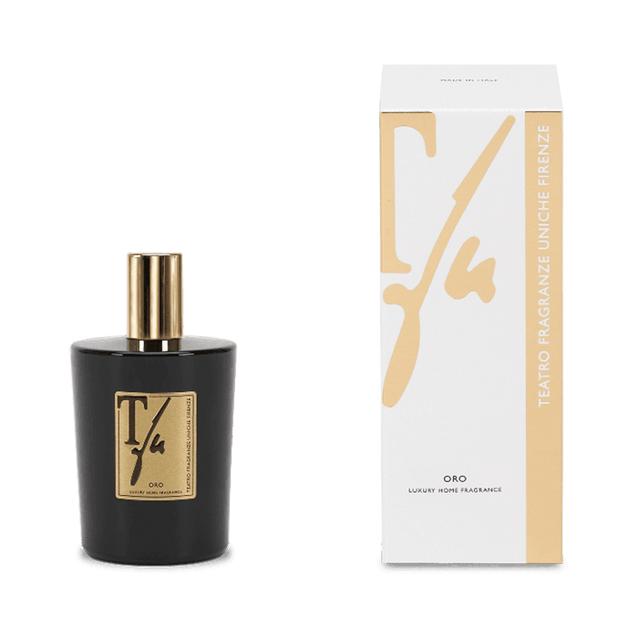 Black perfume bottle with gold cap and label next to its packaging on a green background