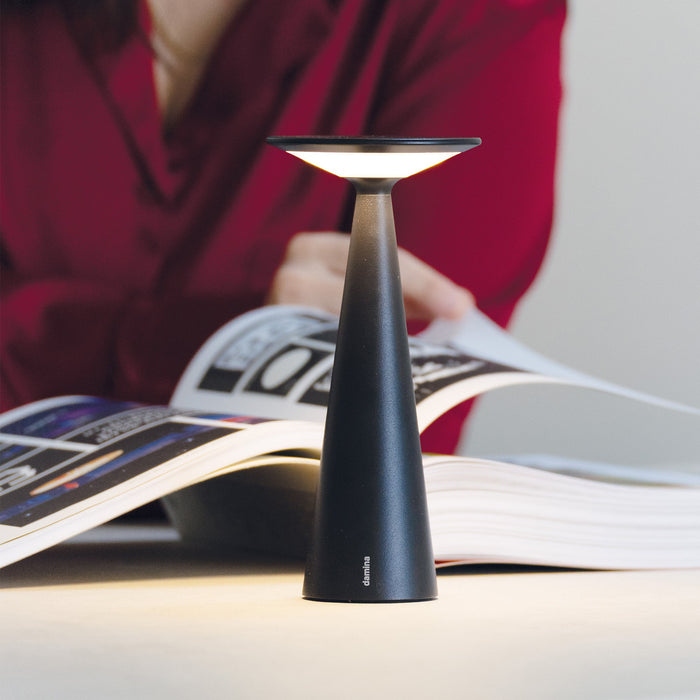 Black lamp on an open book with a blurred person in a red shirt in the background