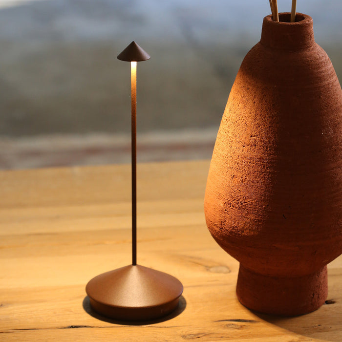 Modern lamp and terracotta vase on a wooden surface with a blurred natural background