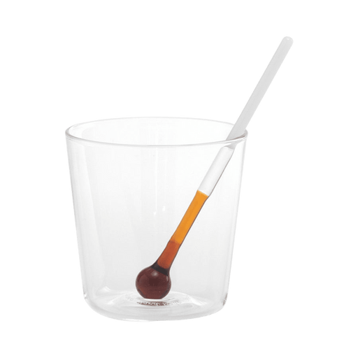Clear glass with a small spoon on a green background