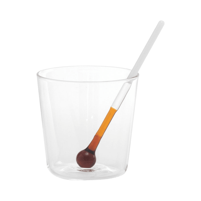 Clear glass with a small spoon on a green background