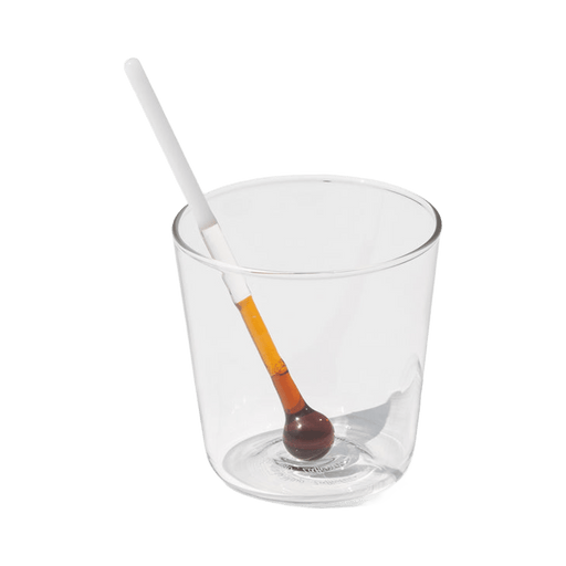 Clear glass with a white straw and a small brown object inside on a green background