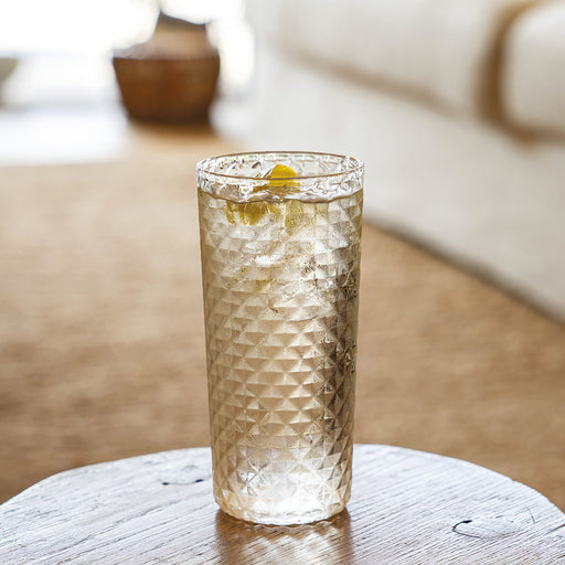 Clear glass with a textured pattern on a wooden surface, blurred background