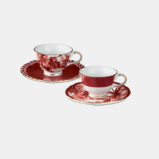 Two red and white ceramic tea cups with saucers on a light gray background