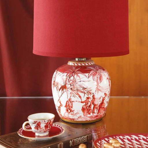 Decorative lamp with red and white design on a table with a cup and saucer.