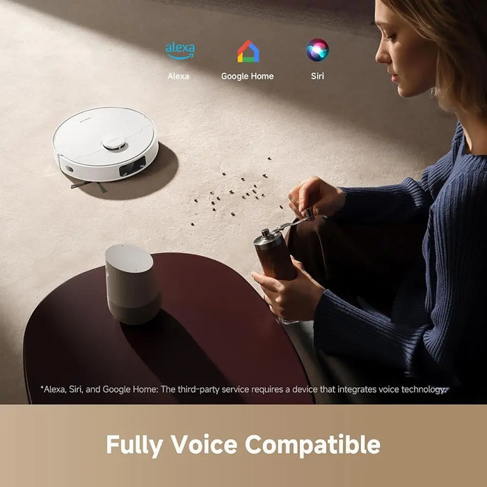 Woman using a coffee grinder with a robot vacuum cleaner on a table, featuring voice compatibility with Alexa, Google Home, and Siri.