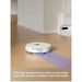 Robotic vacuum cleaner on a wooden floor with text describing its cleaning capabilities.