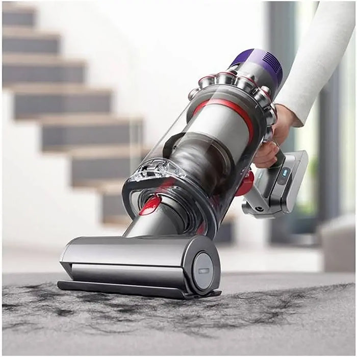 Person using a Dyson vacuum cleaner on a marble floor with blurred stairs in the background