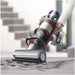 Person using a Dyson vacuum cleaner on a marble floor with blurred stairs in the background