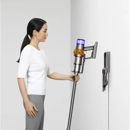 Woman using a Dyson vacuum cleaner against a white background