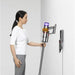 Woman using a Dyson vacuum cleaner against a white background
