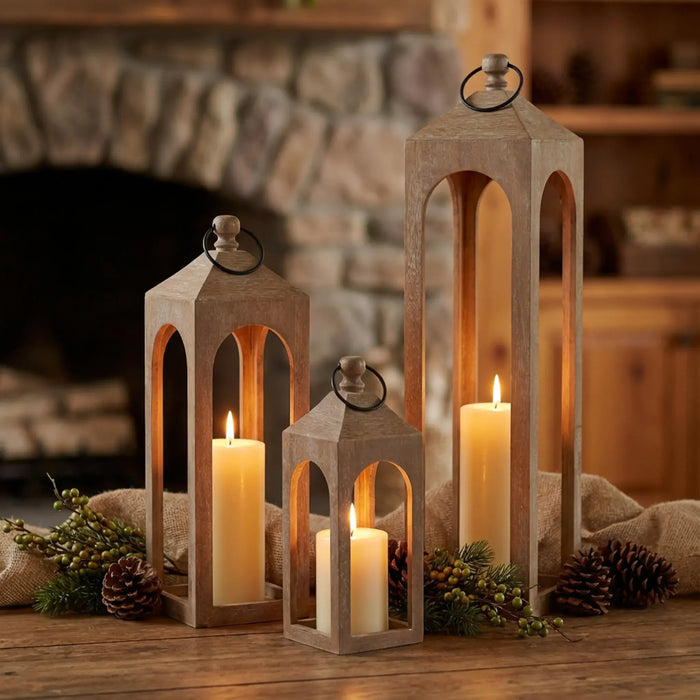 Wooden lanterns with candles on a wooden surface in front of a fireplace.