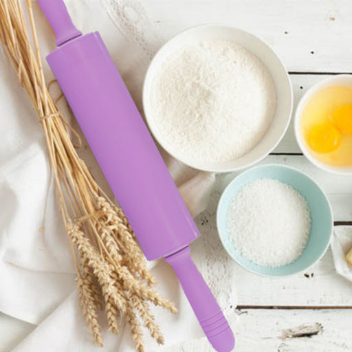 Purple rolling pin on a table with flour, eggs, and wheat stalks.