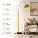 Gold arched floor lamp with a dome shade and round black marble base, shown in a styled living room with callout text listing features like premium metal lampshade, elegant arc design, durable metal frame, heavy marble base, inline foot switch, E26 bulb compatible, and stable sturdy construction.
