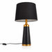 A modern table lamp with a black fabric drum shade, a matte black tapered base, and polished gold metal accents at the neck and bottom, shown on a white background with its power cord visible.