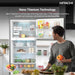 Person standing in front of a Hitachi refrigerator with Nano Titanium Technology, holding vegetables.