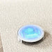 Round device with glowing blue light on a textured surface