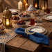 Decorative table setting with candles, lanterns, and food on a wooden table.