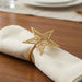 Gold star-shaped napkin ring on a white napkin with a wooden table background