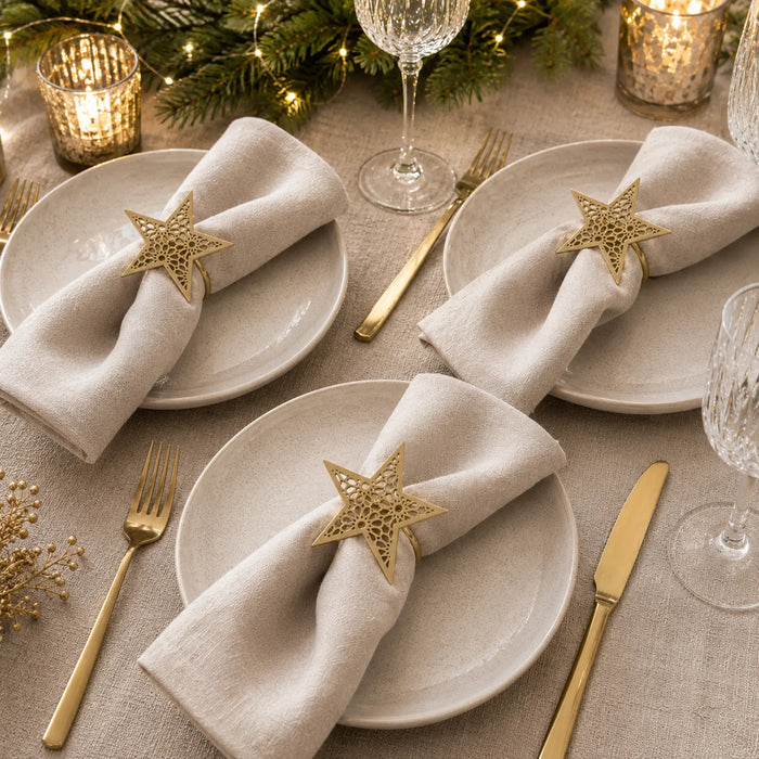 Decorative table setting with star-shaped napkin rings, plates, and cutlery on a festive background.