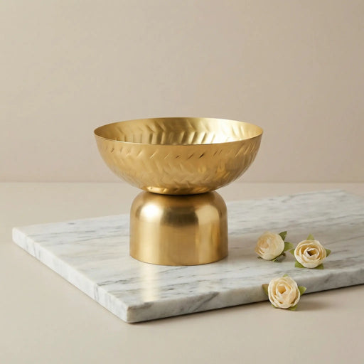 Gold decorative bowl on a marble surface with flowers