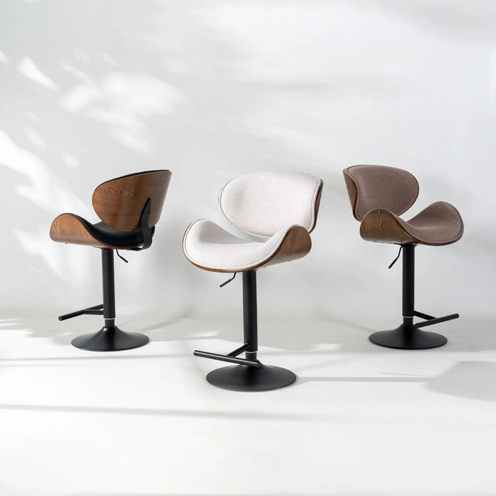 Three modern swivel bar stools with sculptural curved seats and black metal bases, shown on a clean white studio background with soft leaf shadows.