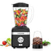 Black blender with a container of chopped vegetables and a container of coffee beans on a white background.