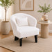 White armchair in a living room with a side table, plants, and framed art.