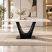 A modern rectangular dining table with a white marble top and a sculptural black U-shaped pedestal base, styled in a bright, contemporary dining room with a beige rug and abstract wall art.