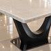 Close-up of a modern dining table with a light beige marble-look top and a glossy black sculptural pedestal base on a tiled floor.