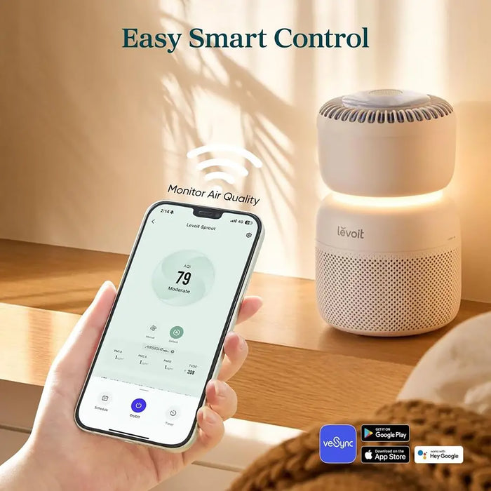 Levoit air purifier with smartphone app for monitoring air quality on a wooden surface.