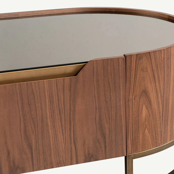 Close-up of a modern wooden sideboard or console table with a warm brown wood grain finish, a curved top, and a brass-toned metal frame and drawer edge.