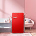 Red refrigerator in a room with pink walls and a sofa.