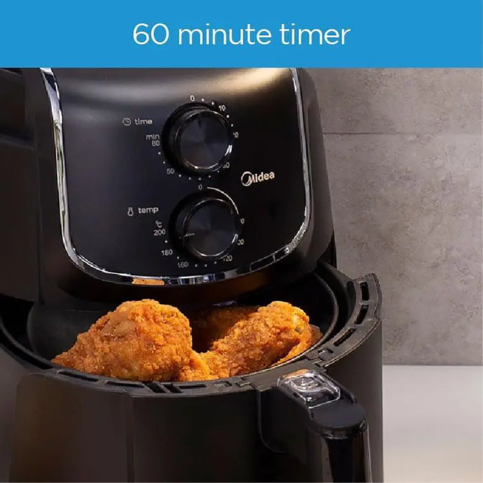 Black Midea air fryer with fried chicken inside, showing a 60-minute timer feature.