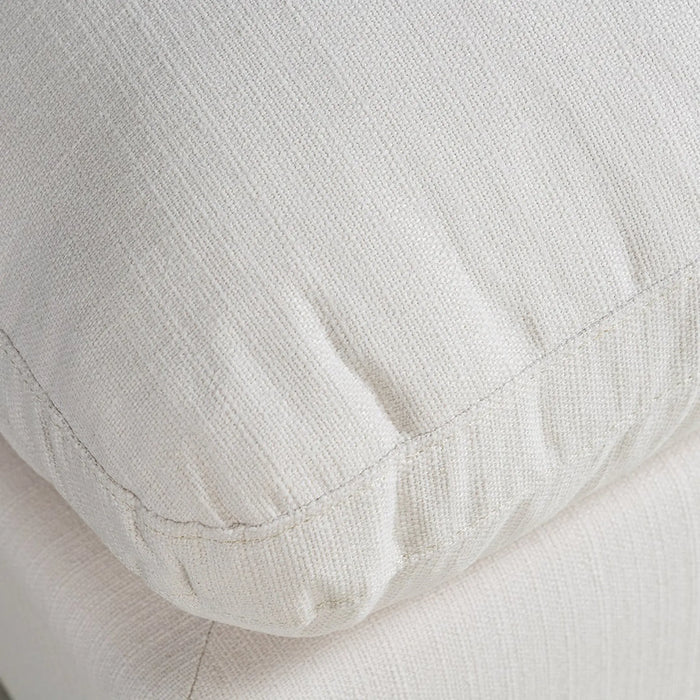 Close-up of a textured off-white fabric cushion with visible stitching and a ribbed edge.