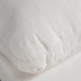 Close-up of a textured off-white fabric cushion with visible stitching and a ribbed edge.