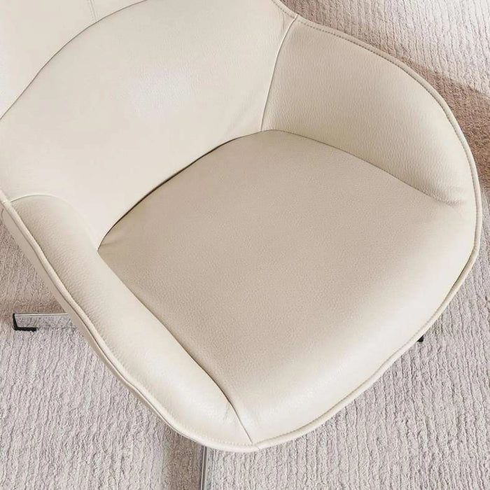 A close-up of a modern upholstered chair in warm off-white leather, showing the seat cushion and curved armrests, with a textured light rug underneath.