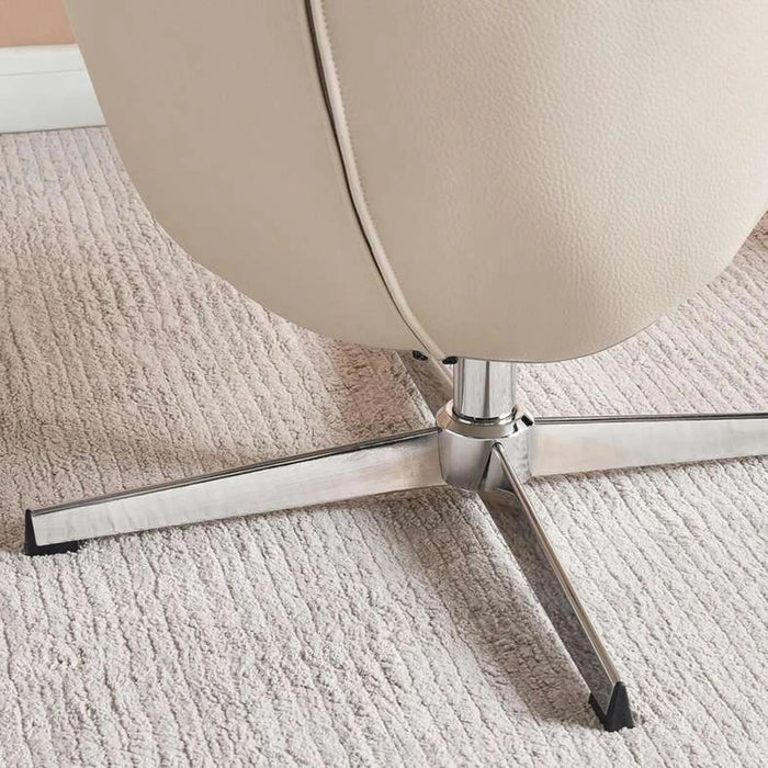 Close-up of a beige chair with a metal base on a textured carpet
