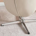 Close-up of a beige chair with a metal base on a textured carpet