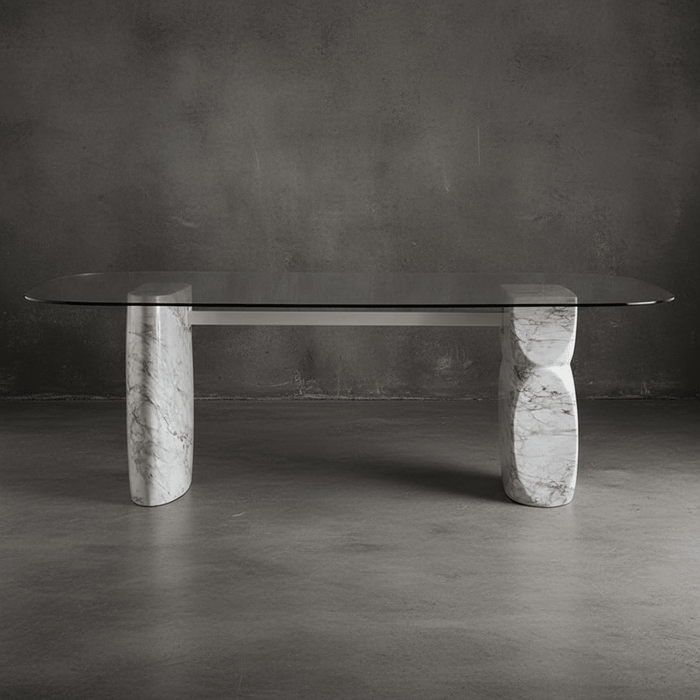 Glass dining table with marble legs against a dark gray wall.