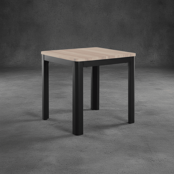 Square table with wooden top and black metal legs on a gray concrete floor.