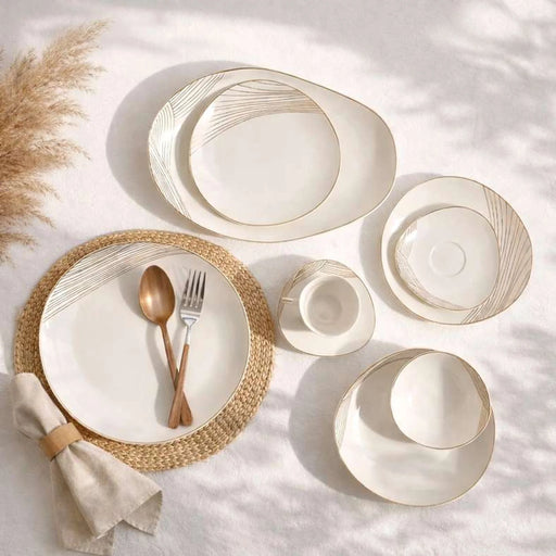 Set of white ceramic plates with gold accents on a light surface.