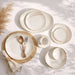 Set of white ceramic plates with gold accents on a light surface.