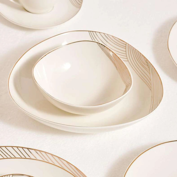 Set of white ceramic plates with gold rim on a matching white background
