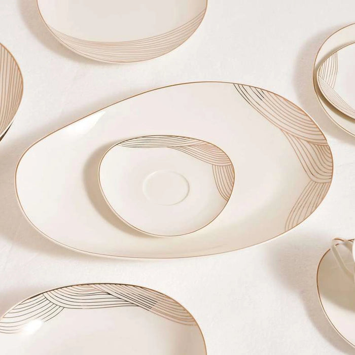 Set of cream-colored ceramic plates with gold decorative lines on a light beige background