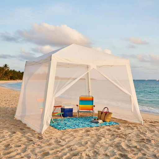 Beach tent with colorful chair and beach accessories on a sandy beach.