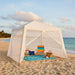 Beach tent with colorful chair and beach accessories on a sandy beach.