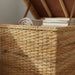 Woven basket with books and a towel inside, on a neutral background