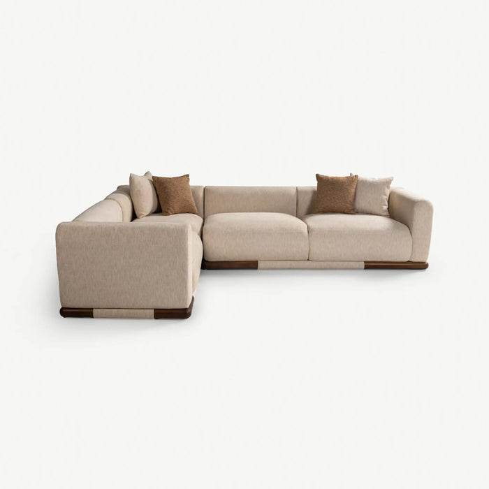 A modern L-shaped sectional sofa in light beige fabric with dark brown wooden accents on the base and legs, styled with four brown throw pillows, set against a plain white background.