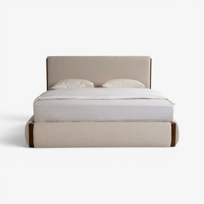 A modern platform bed with a low upholstered headboard and footboard in a light beige fabric, styled with white bedding and two pillows against a clean white background.